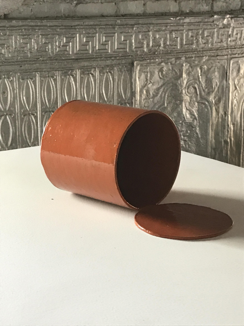 orange can lying horizontally on pedestal with open lid
